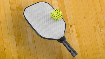 A pickleball paddle and a pickleball on the indoor courts at SJC HHPC.