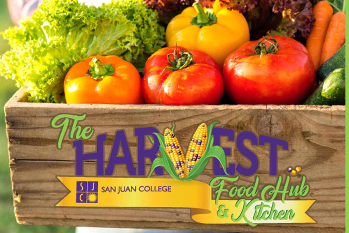 The Harvest Food Hub San Juan College wooden box with fresh produce inside, red tomatoes, lettuce, orange and yellowbell peppers