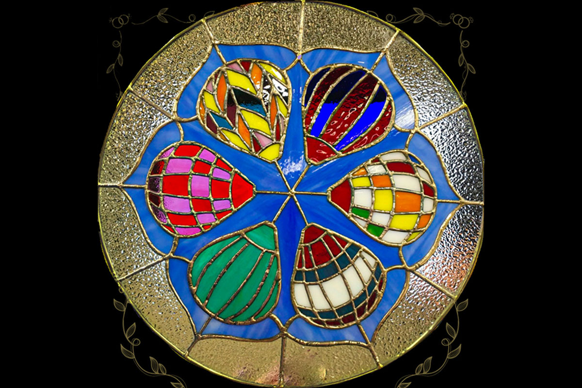 Stained glass round piece featuring hot air balloons in a variety of colors