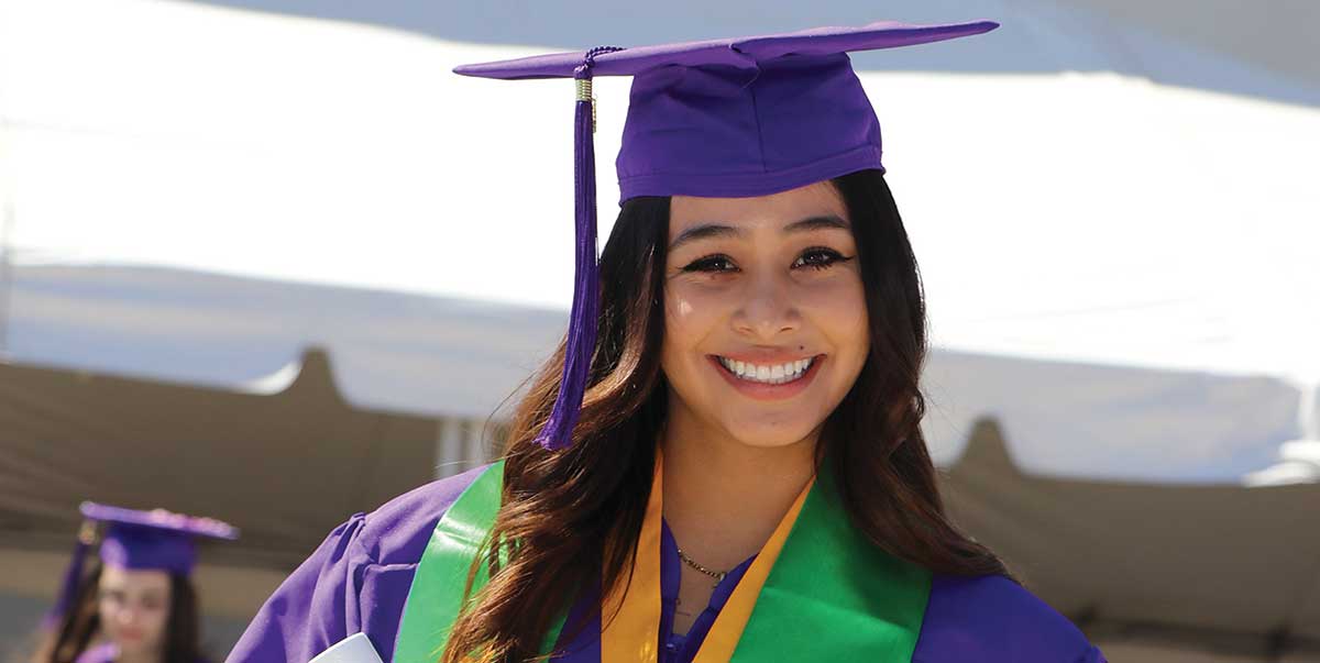 Graduate from San Juan College Standing in cap and gown holding diploma