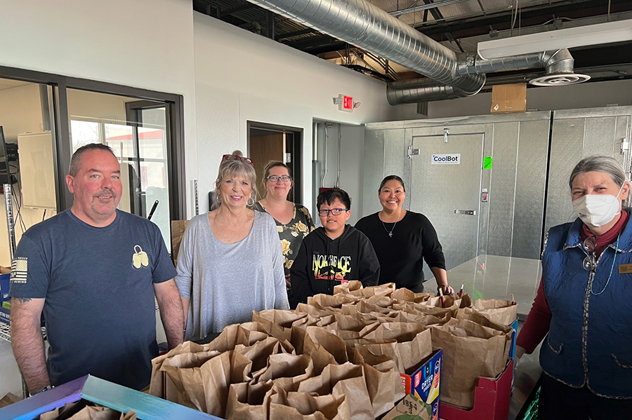 Individuals standing together in front of made sack lunches