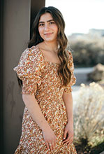 Bria Cohen leaning against pillar smiling at camera