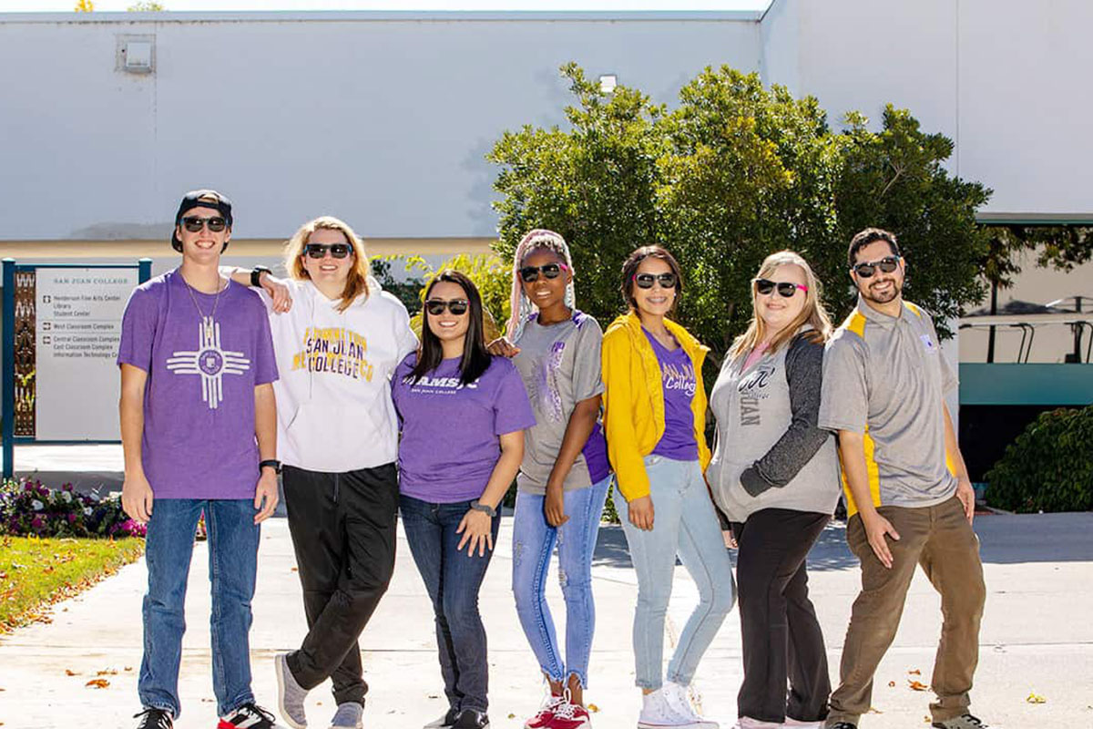 smiling sjc students in a row in the courtyard area