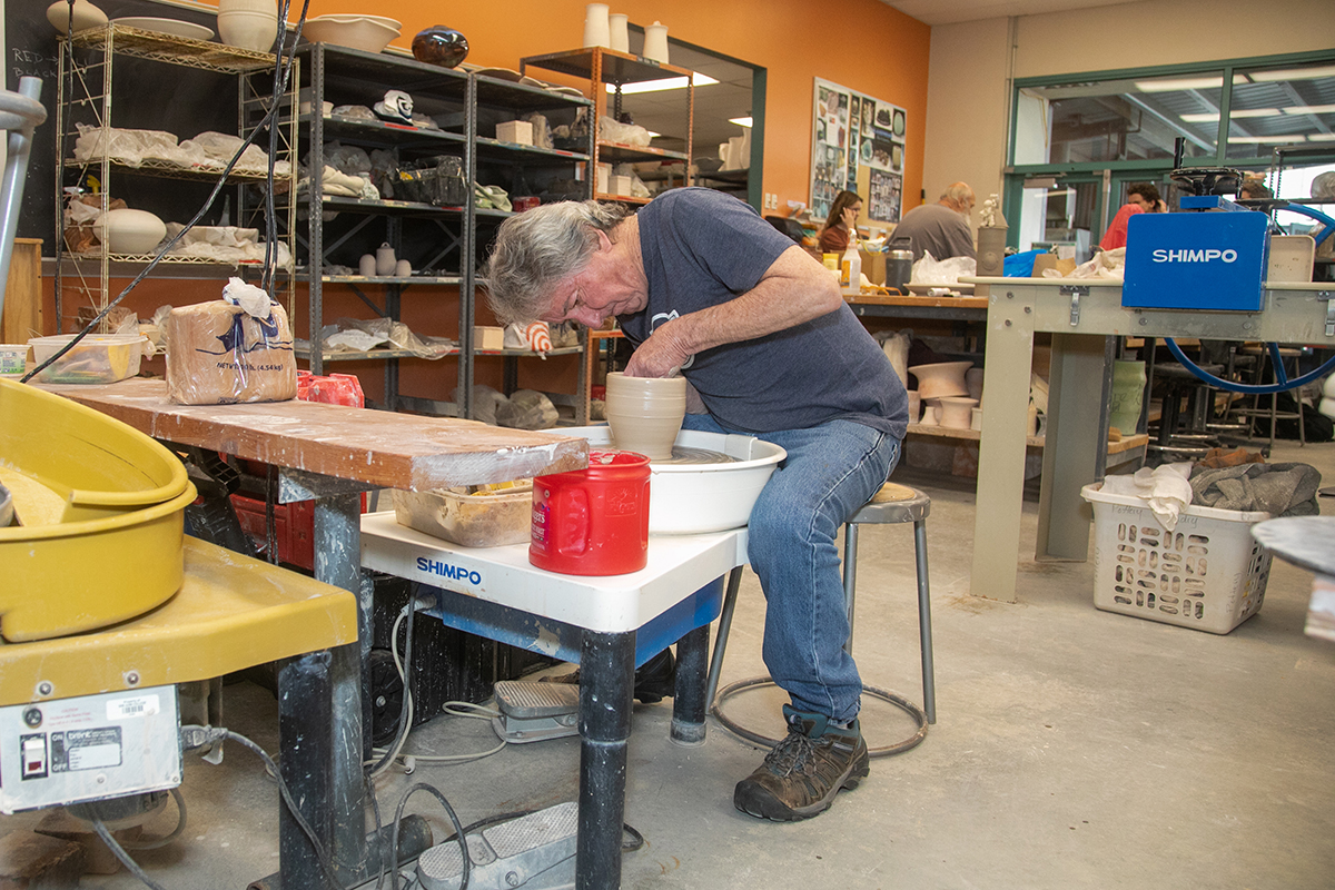 Man using pottery throwing wheel.