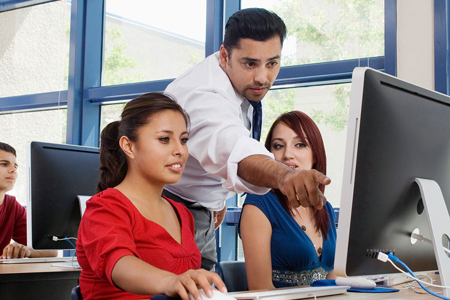 Teacher pointing over student at computer