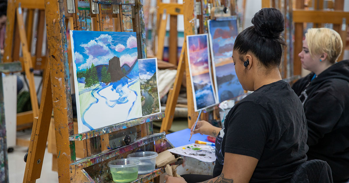 Students work on painting in art studio.