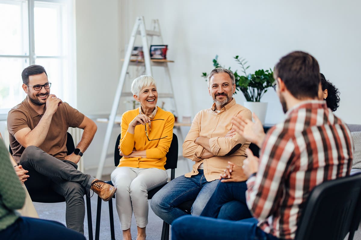 A therapist leading a group counseling session with a diverse group of people sitting in a circle