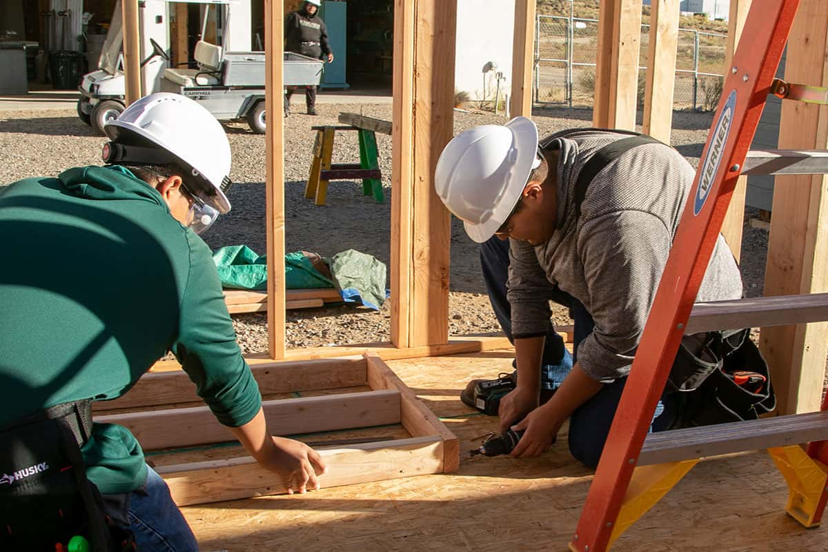 Two San Juan College students working on framing a building