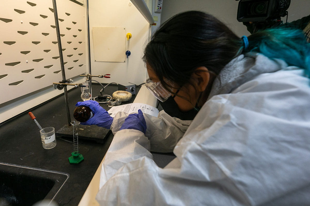 A San Juan College student pouring a liquid into a test tube in a chemistry lab