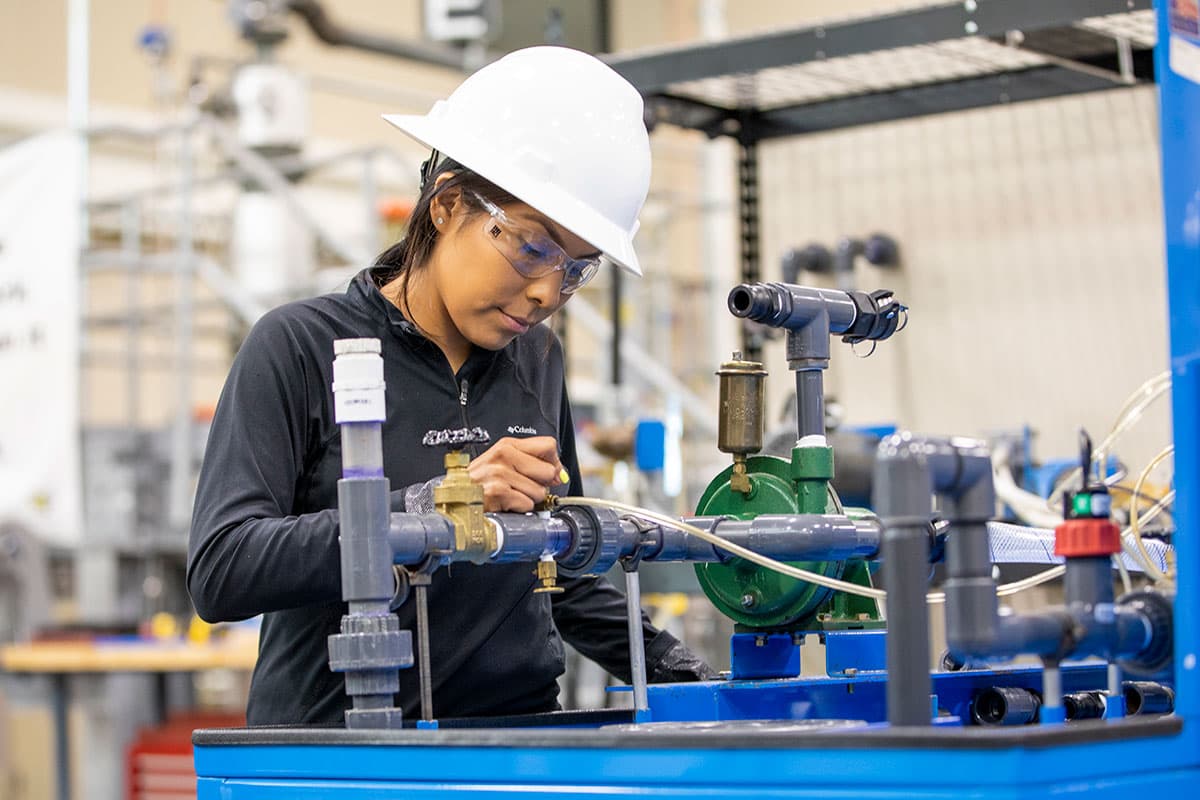 An individual in a hard hat inspects valves and equipment