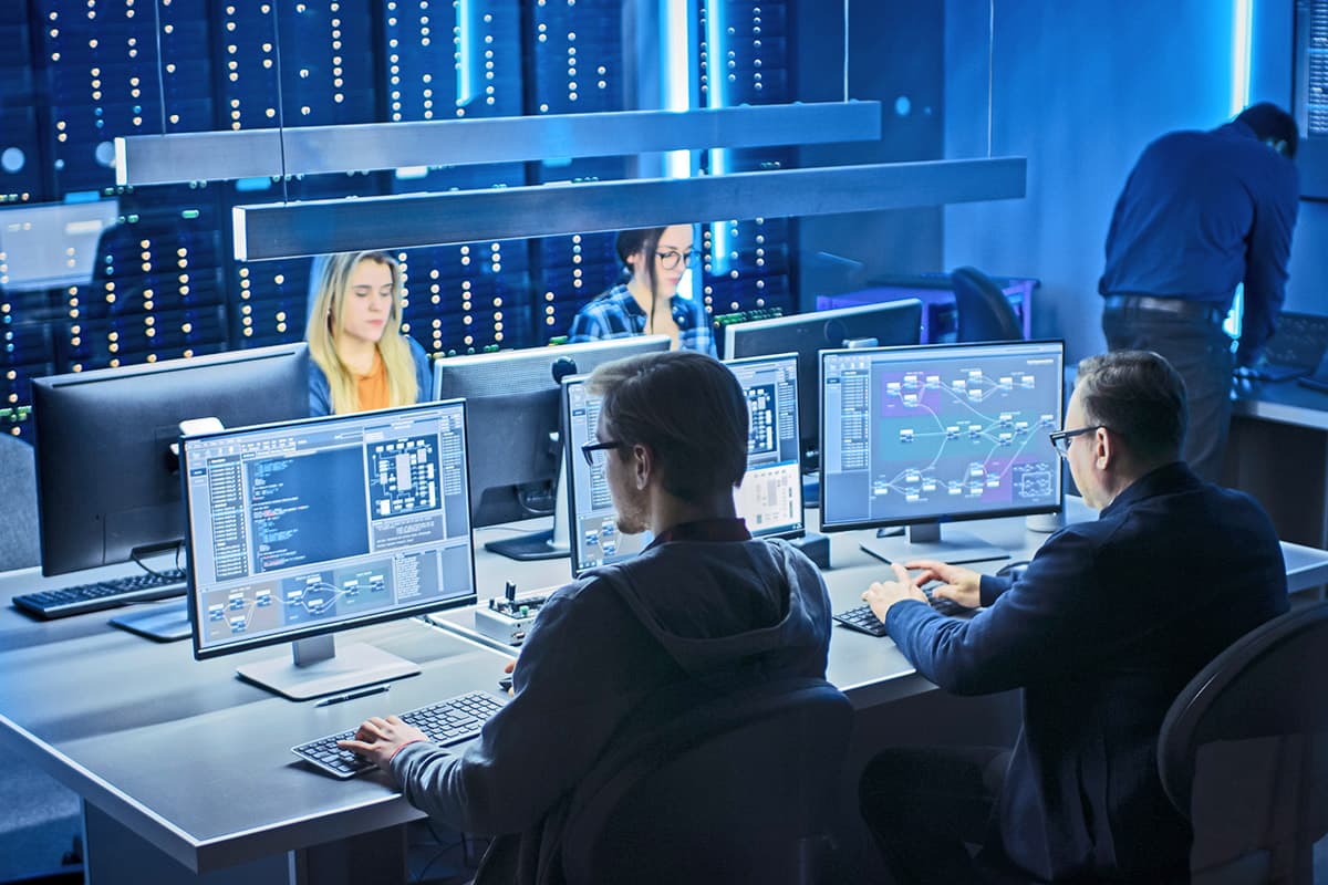 IT professionals working on a bank of computers in a tech lab