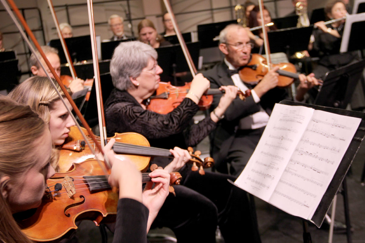 Multiple students playing violins with sheet music on stand