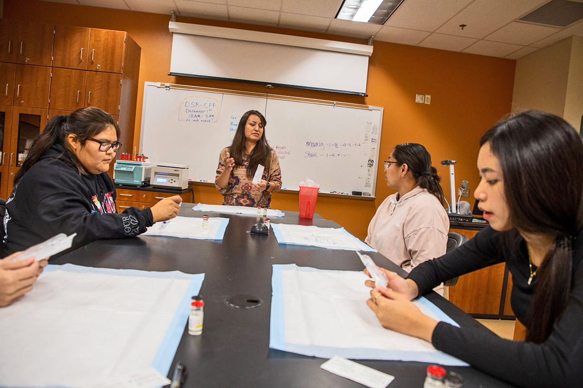 Instructor leads students through classwork involving injectable medication.