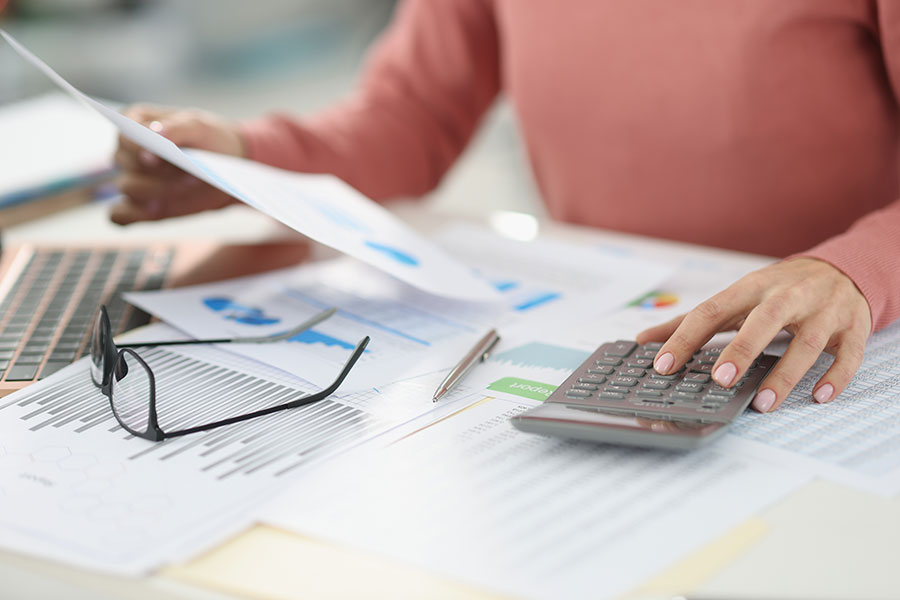 A San Juan College student using a calculator to check numbers on printed accounting charts