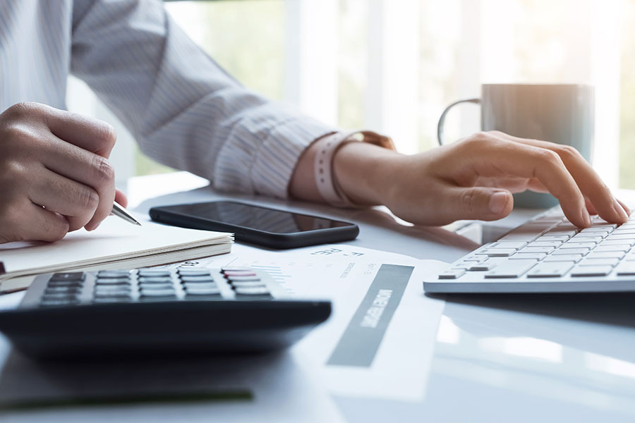 Accounting professional on calculator an laptop.