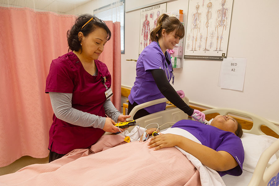 Two students standing beside a hospital bed