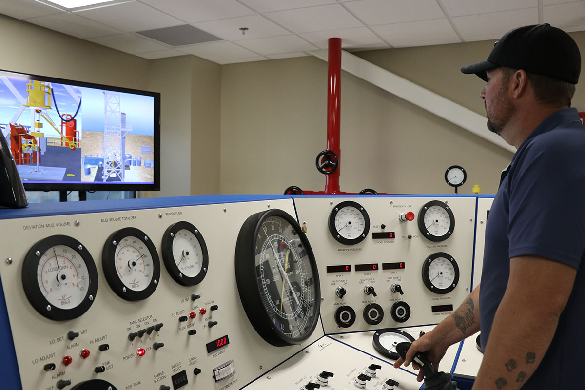 Oilfield worker standing at multi control panel